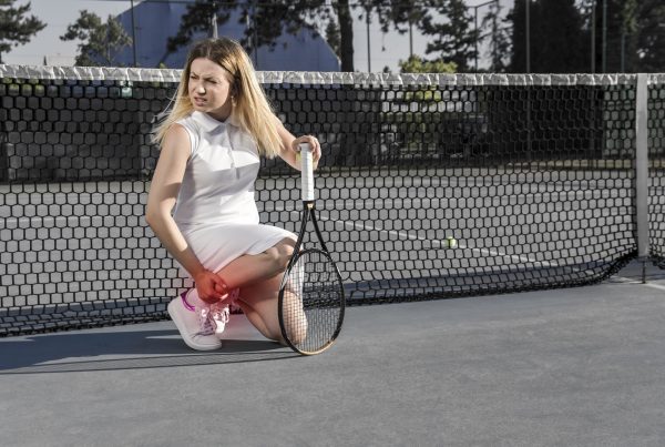 Injured female tennis player, feeling pain in her leg