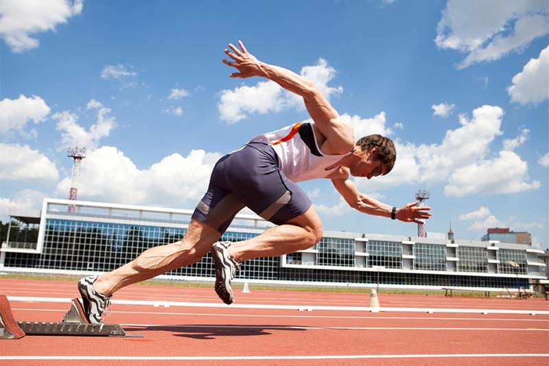 young muscular athlete is at the start of the treadmill at the stadium
